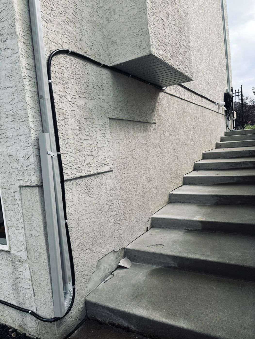 Exterior conduit run neatly strapped along a stucco wall